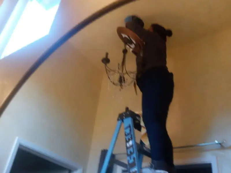 Electrician installing a chandelier in a Iona residence